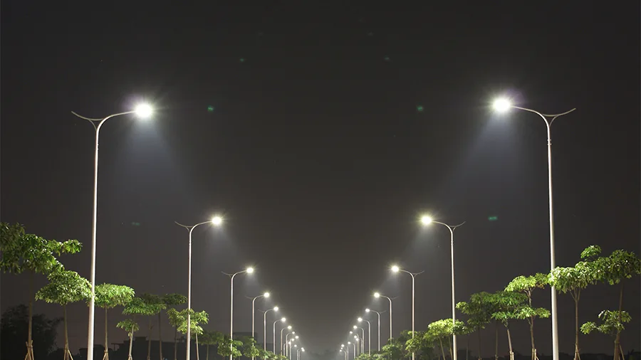 Road at night lit from both sides by street lighting, with an even pool of light along the carriageway